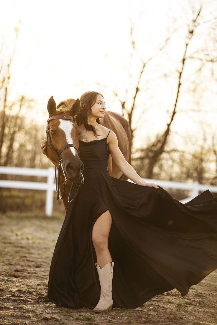 a woman in a black dress is walking with a horse