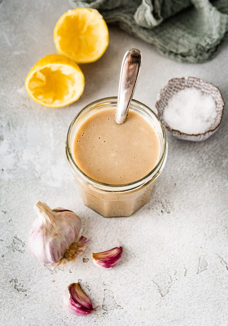 a jar filled with liquid next to garlic and lemons