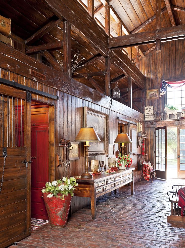 a room with wooden walls and brick flooring in the center is decorated with potted plants