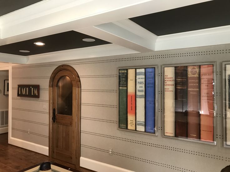 a room with several books on the wall and a door in the center that leads to another room