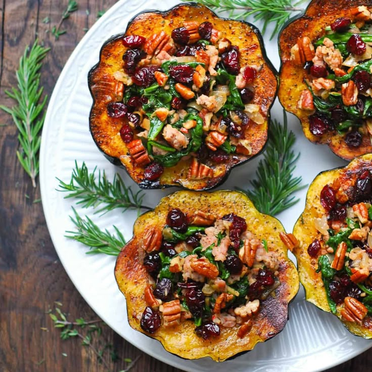 three stuffed acorns on a white plate topped with cranberries and pecans