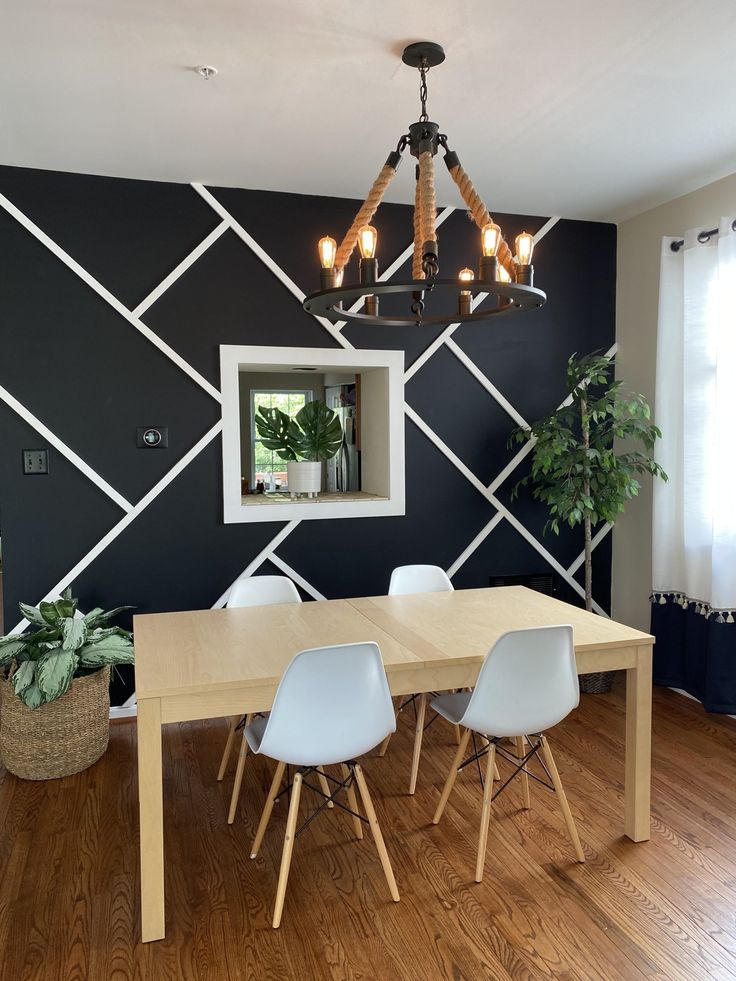 a dining room table with four chairs and a mirror on the wall