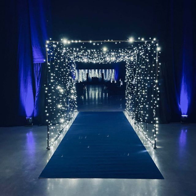 a blue and white wedding aisle decorated with fairy lights, draping down the middle