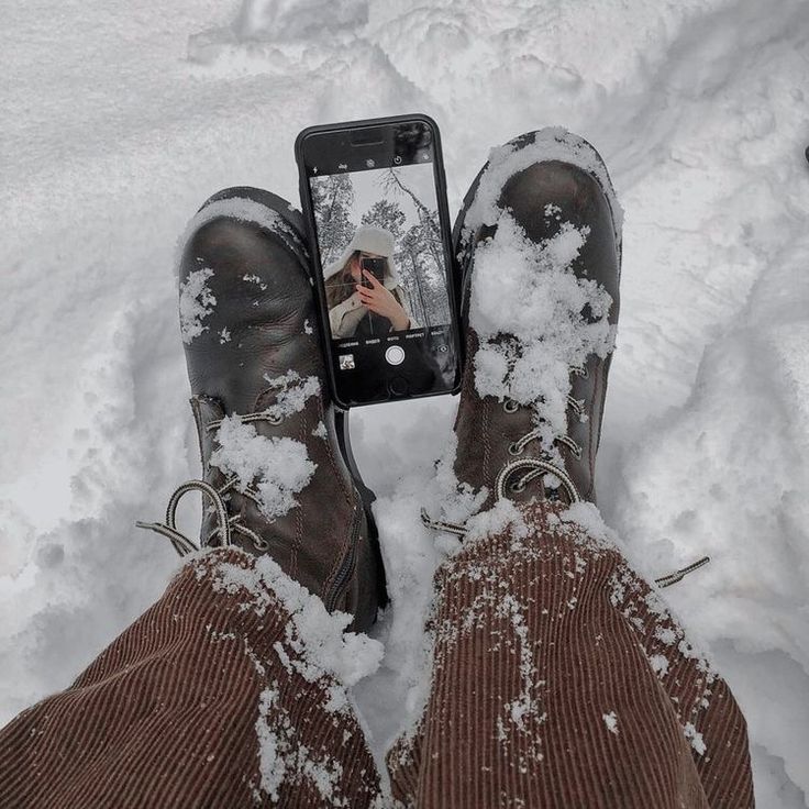 someone is taking a selfie in the snow with their feet covered in snow and holding a cell phone