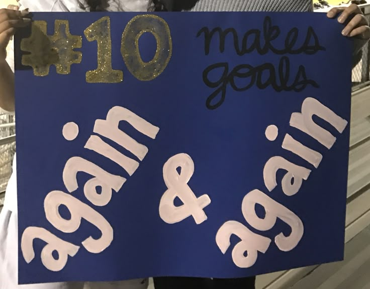 two people holding up a sign that says make goals and man & woman