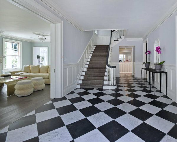 an entryway with black and white checkered flooring, stairs leading up to the second floor