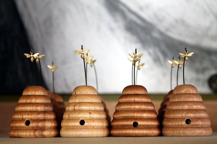 three wooden beehives with flowers in them on a table next to a wall