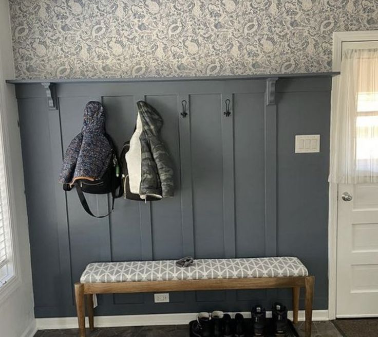 a bench and coat rack in a room with blue wallpaper on the walls behind it