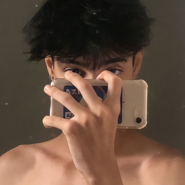 a shirtless man holding up his cell phone to take a selfie in the mirror