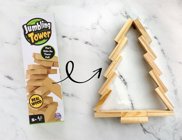 a wooden christmas tree next to a box of dominos on a marble counter top