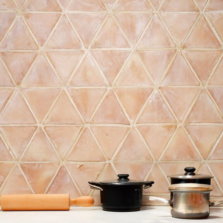 pots and pans are sitting on a counter top next to a wall with geometric tiles