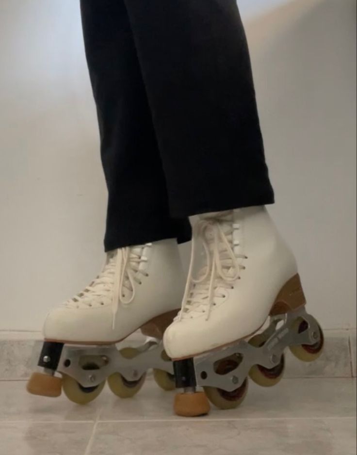 the legs of a person riding roller skates on a tile floor in front of a white wall