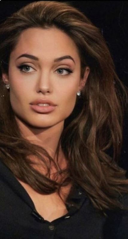 a woman with long brown hair posing for a photo in front of a black background