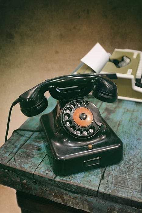 an old fashioned phone sitting on top of a wooden table