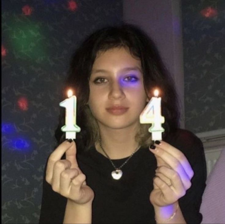 a woman holding two candles in front of her face with the number one on them