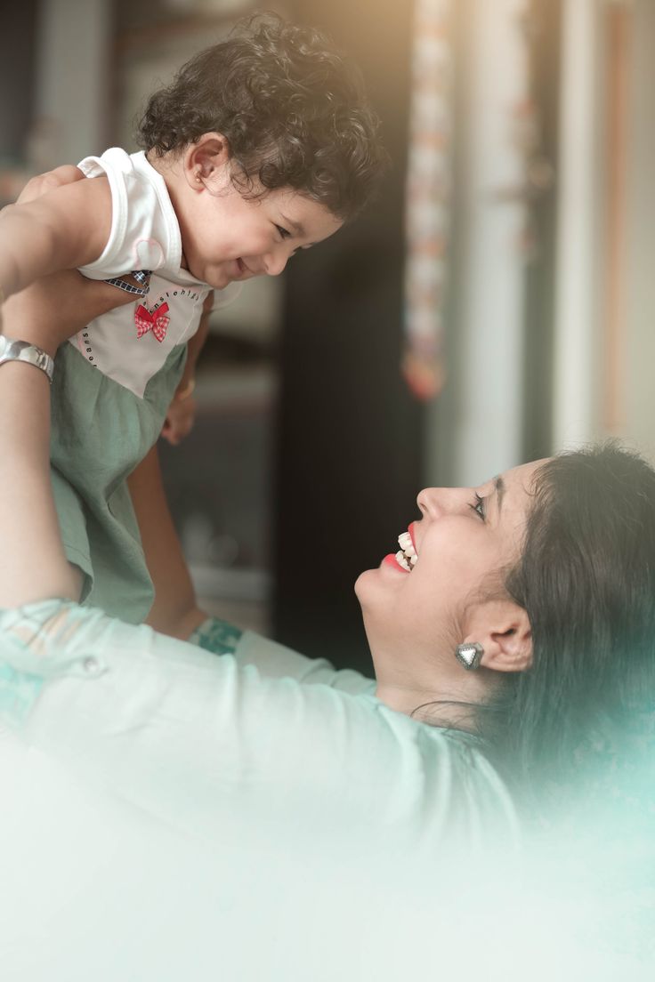 a woman holding a small child up to her face while she smiles at the camera