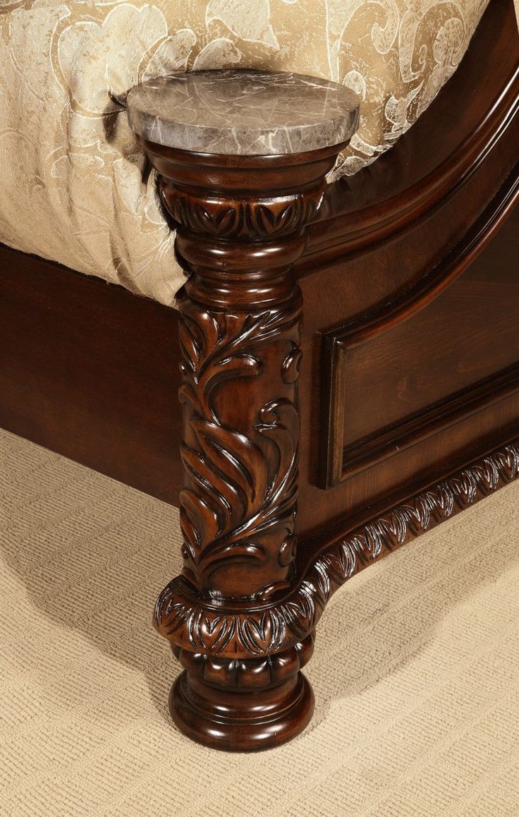 an ornate wooden bed frame with marble top