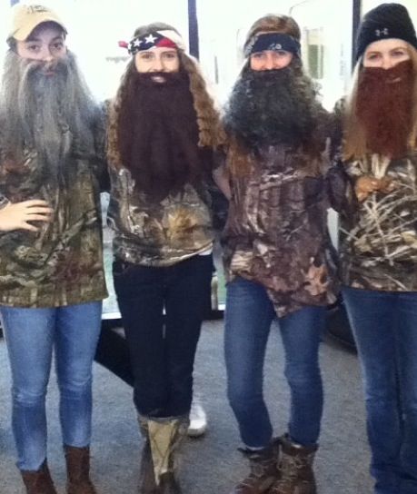 four people dressed in duck hunting gear posing for a photo with their heads covered by fake beards