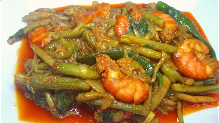 a white plate topped with green beans and shrimp covered in sauce on top of it