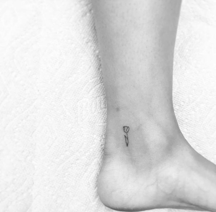 a small flower tattoo on the ankle is shown in black and white, as well as an arrow