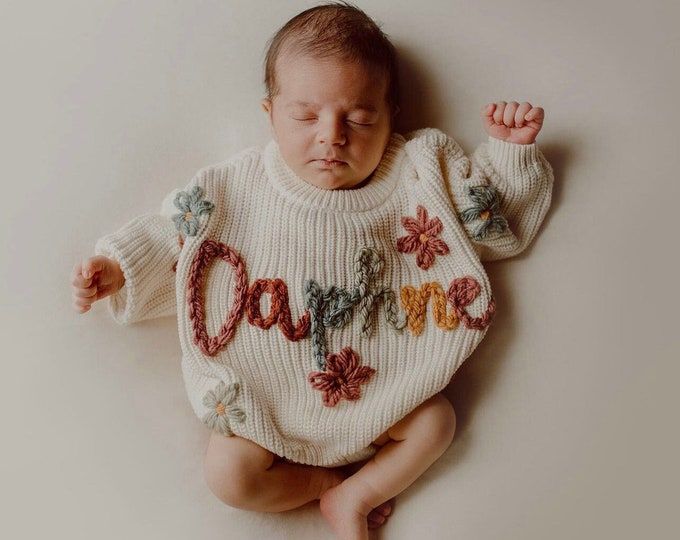 a newborn baby wearing a sweater with the word love on it's chest and hands