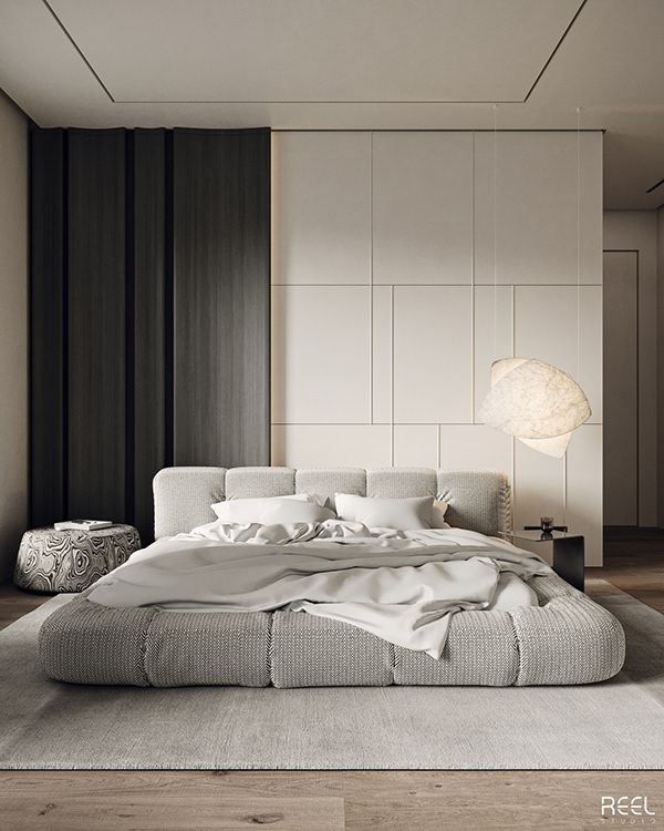 a large bed sitting on top of a wooden floor next to a white chair and lamp