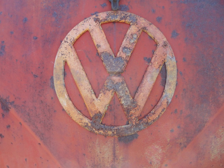 an old rusty vw emblem on the side of a red vehicle