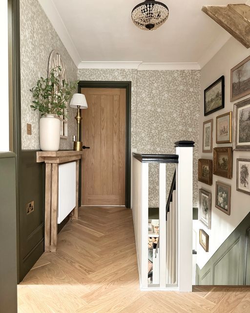 an entry way with pictures on the wall and wooden stairs leading up to it's door