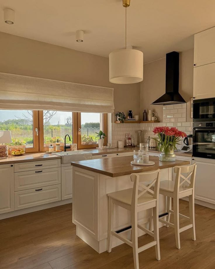 a kitchen with white cabinets and an island in front of a stove top oven next to a window