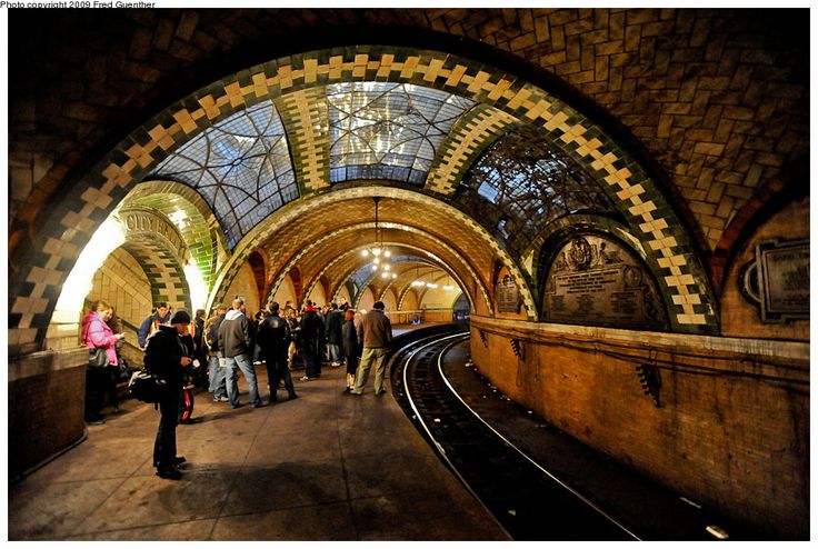 people are standing in the middle of an underground train station with arched ceilings and stone arches