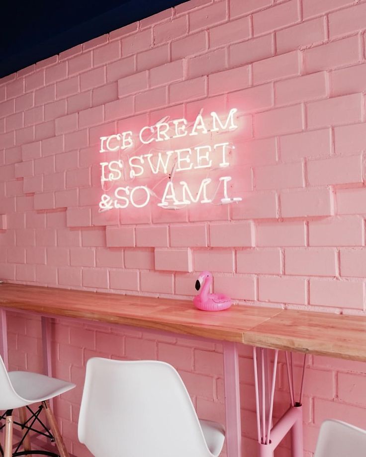 pink brick wall with neon sign and chairs