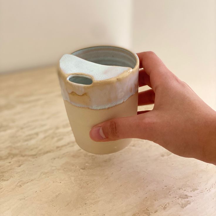 a hand holding a cup with something in it