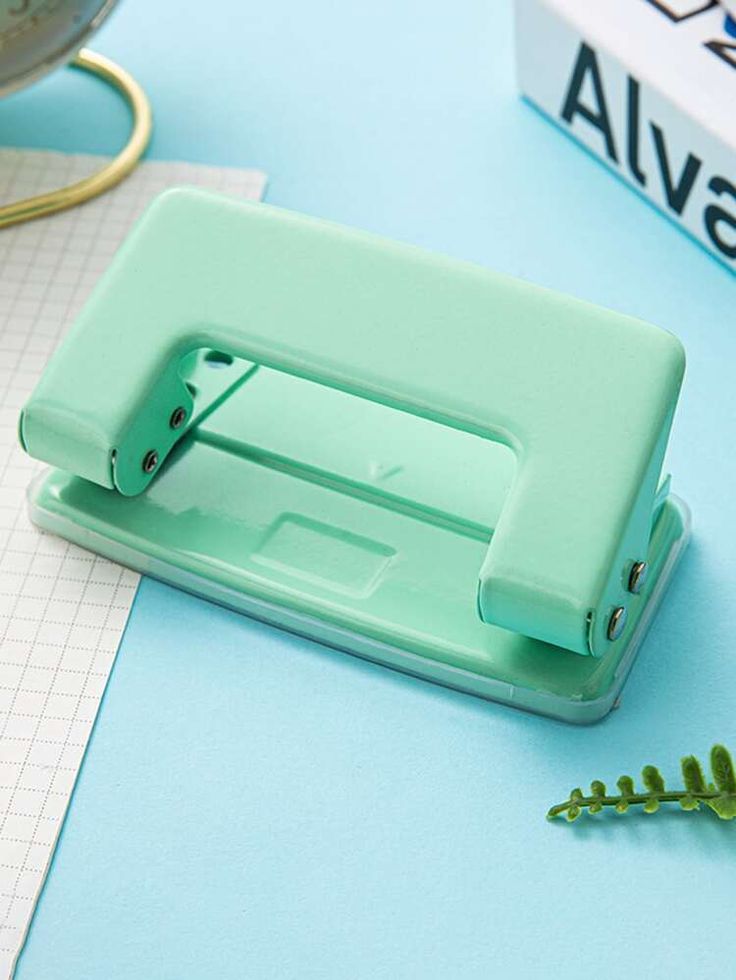 a green stapler sitting on top of a blue table next to a pair of scissors