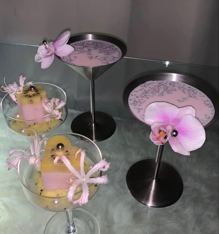 three desserts in glass dishes with pink flowers on the top and one is decorated like a bird