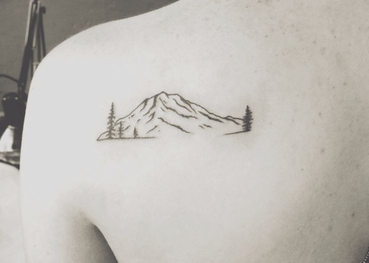 the back of a woman's shoulder with a mountain tattoo on it