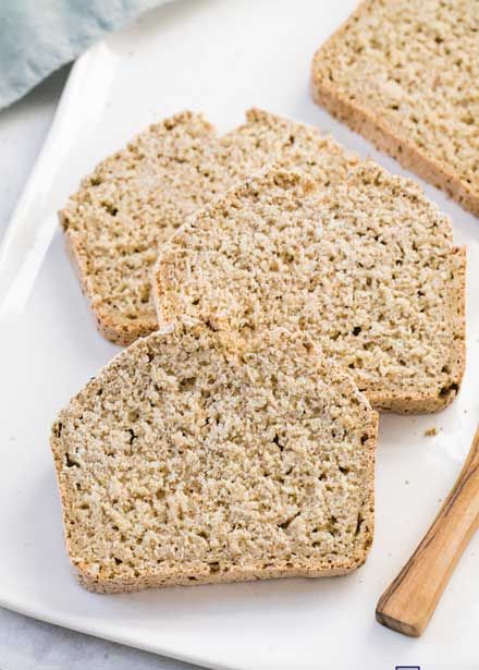 three slices of bread on a white plate next to a wooden spoon and napkins