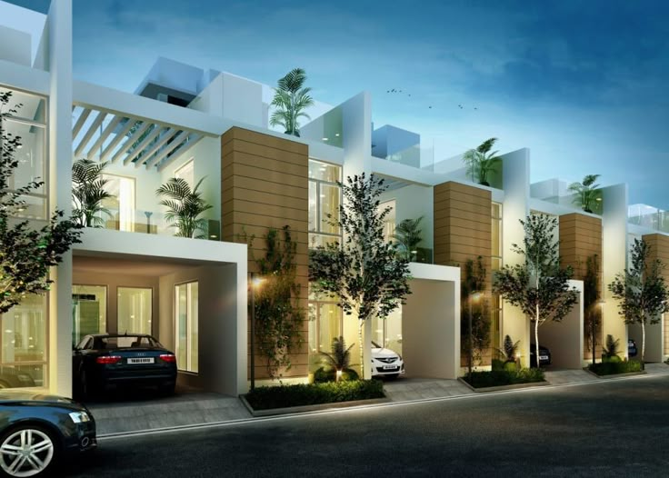 a car is parked in front of a row of townhouses at night with lights on