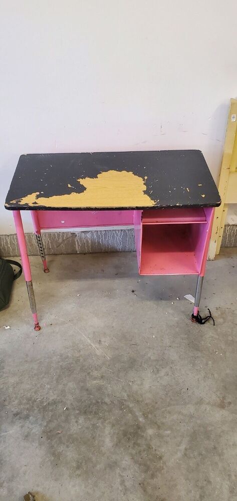 an old desk is painted pink and black with yellow spots on the top, next to a chair