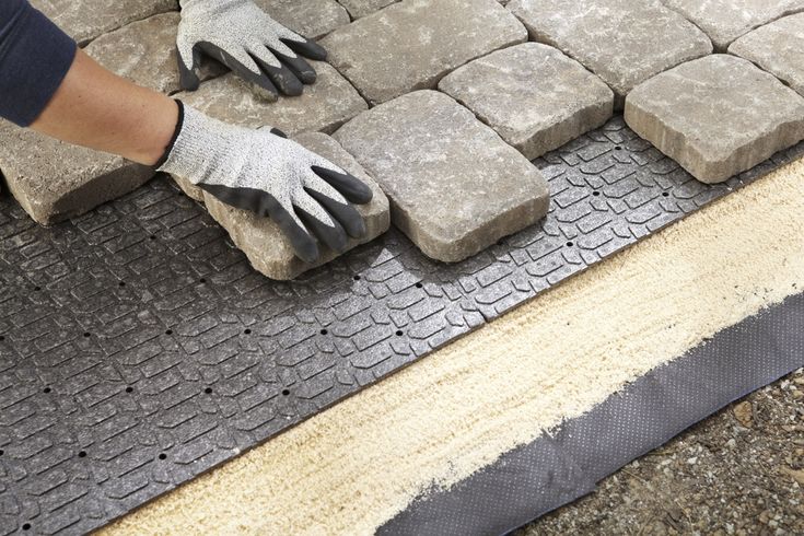 a person wearing gloves and work gloves laying on some cement blocks in the middle of a floor