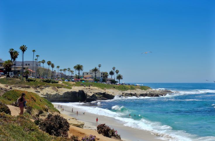 people are walking on the beach near the ocean