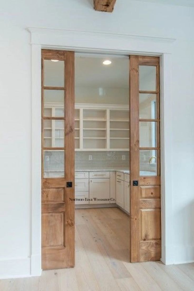 an open door leading to a kitchen with white cabinets and wood floors in the background