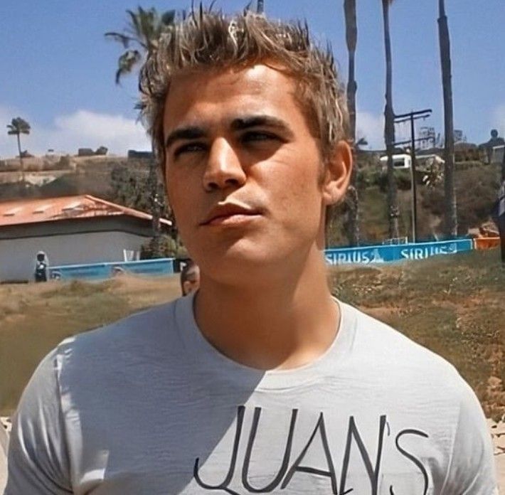 a young man standing in front of some palm trees