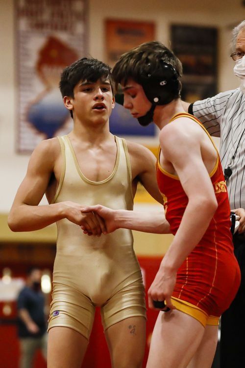 two men in wrestling uniforms standing next to each other with one man wearing a face mask