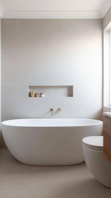 a large white bathtub sitting next to a toilet in a bathroom under a window