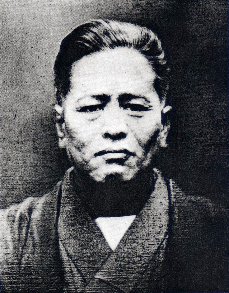 an old black and white photo of a man wearing a kimono with his eyes closed