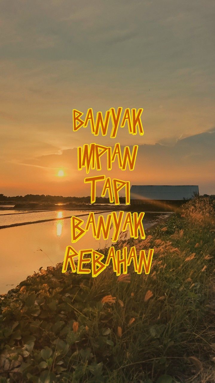 the words are written in neon yellow letters on grass near water at sunset or dawn