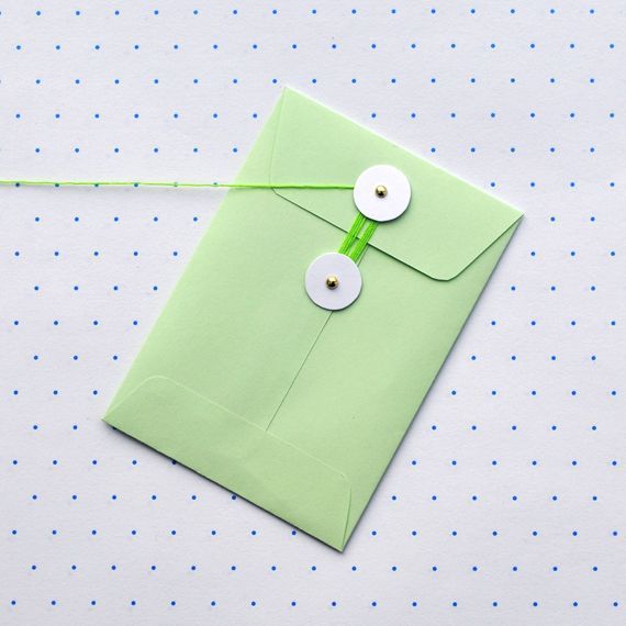 a green envelope with two white buttons on it and a string attached to the front