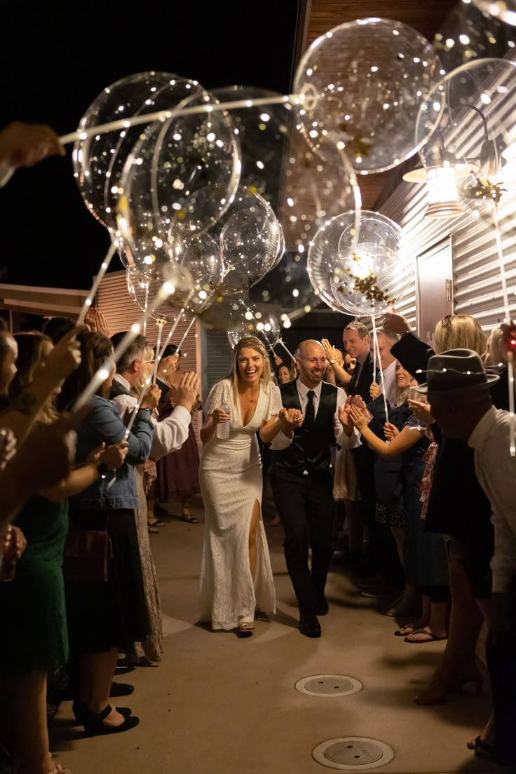 a bride and groom walk down the aisle with bubbles in their hands as they exit