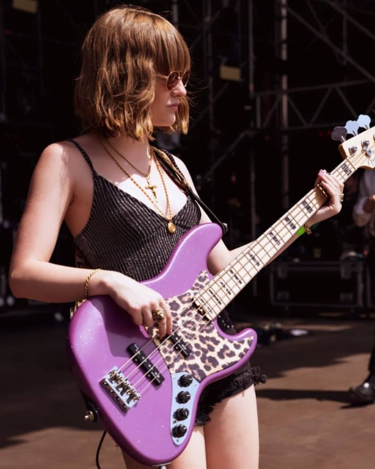 a woman holding a purple guitar on stage