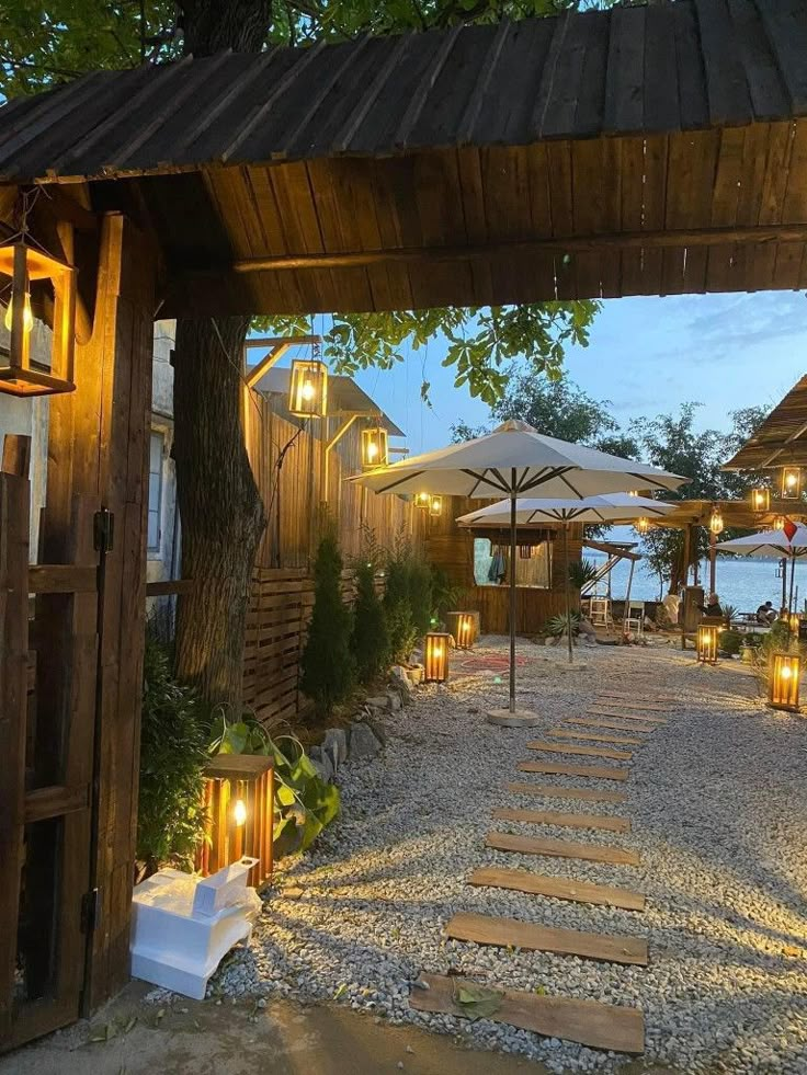 an outdoor area with tables, chairs and umbrellas lit up at night in the evening